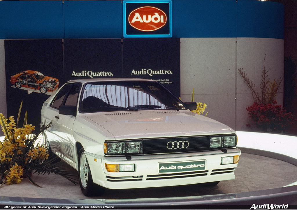 1980: five-cylinder gasoline engine with turbocharger and intercooler: In 1980 at the Geneva Motor Show, Audi unveils the Audi quattro (B2), known as the “Ur-quattro” from the mid-1990s. It uses the powerplant from the Audi 200 5T (C2), but features an intercooler. As a result, the turbocharged engine achieves a higher output of 147 kW (200 hp) at 5,500 revolutions per minute and 285 newton meters (210.21 lb-ft) of torque at 3,500 rpm. The body of the Audi quattro is based on the Audi Coupe (B2), which in turn is based on the Audi 80. Flared fenders, bulkier bumpers and sills as well as a larger rear spoiler distinguish the Audi quattro from the Coupe.